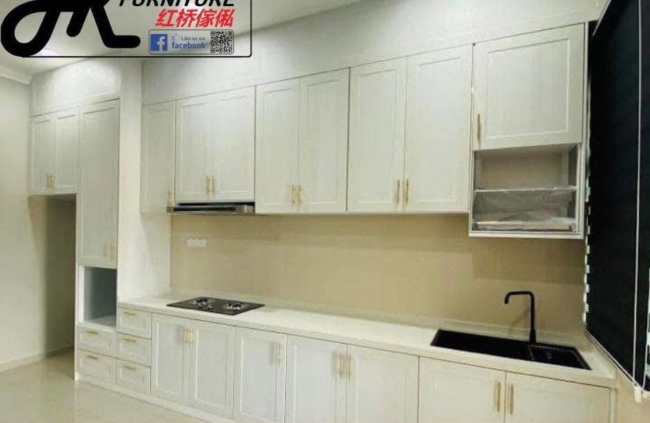 A long single-run cream classic-profile aluminium kitchen with gold bar handles, a full wall of tall units, a glass splashback and a black sink.