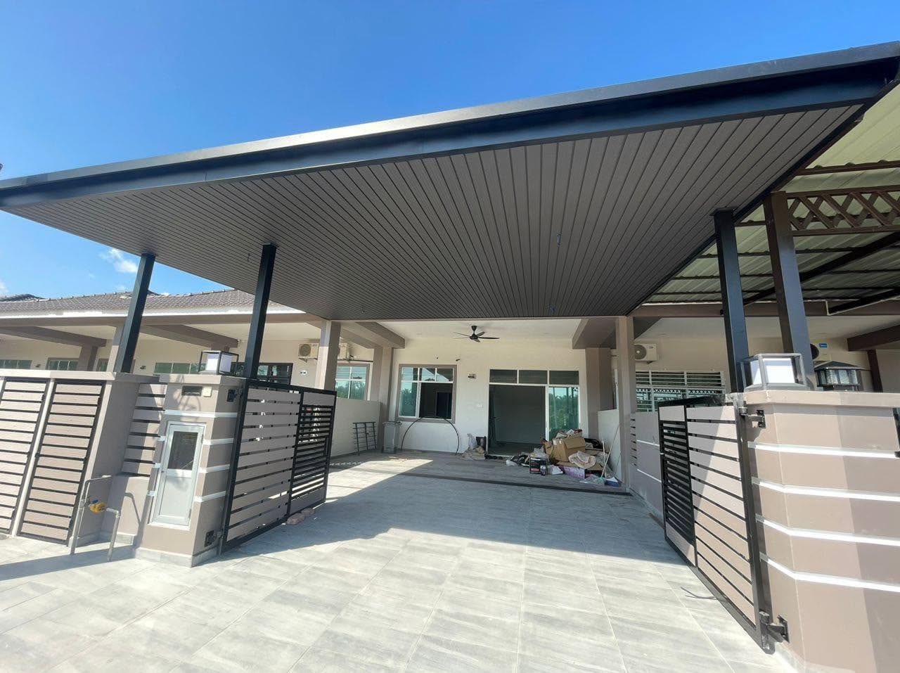 A terrace-house car porch under a wide steel-framed roof lined with dark grey slatted panels, matching slatted gates on both sides, grey porcelain floor tiles, a blue sky.