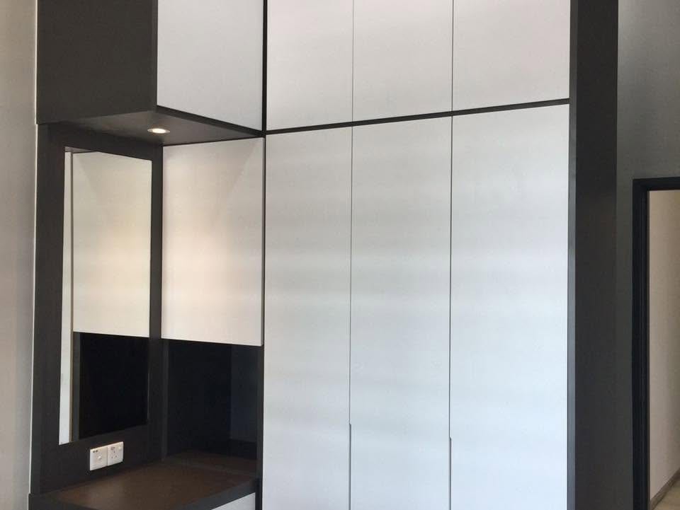 A floor-to-ceiling built-in wardrobe with matte white handleless doors and dark charcoal framing, beside a dressing recess with a framed mirror and a downlight.